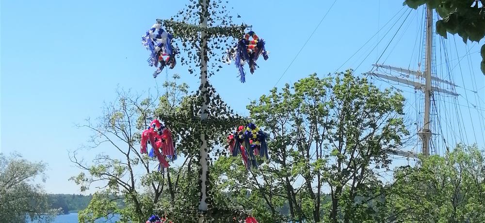 åländsk midsommarstång med båtar i toppen och papperskronor