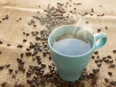 kaffemugg med kaffe på ett bord med kaffebönor