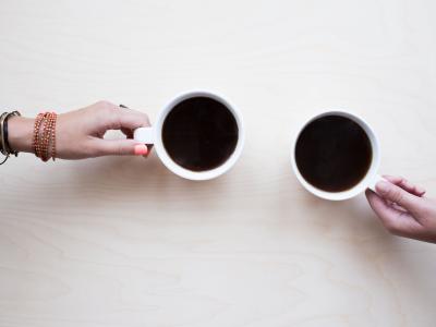 två händer som håller i varsin kaffekopp